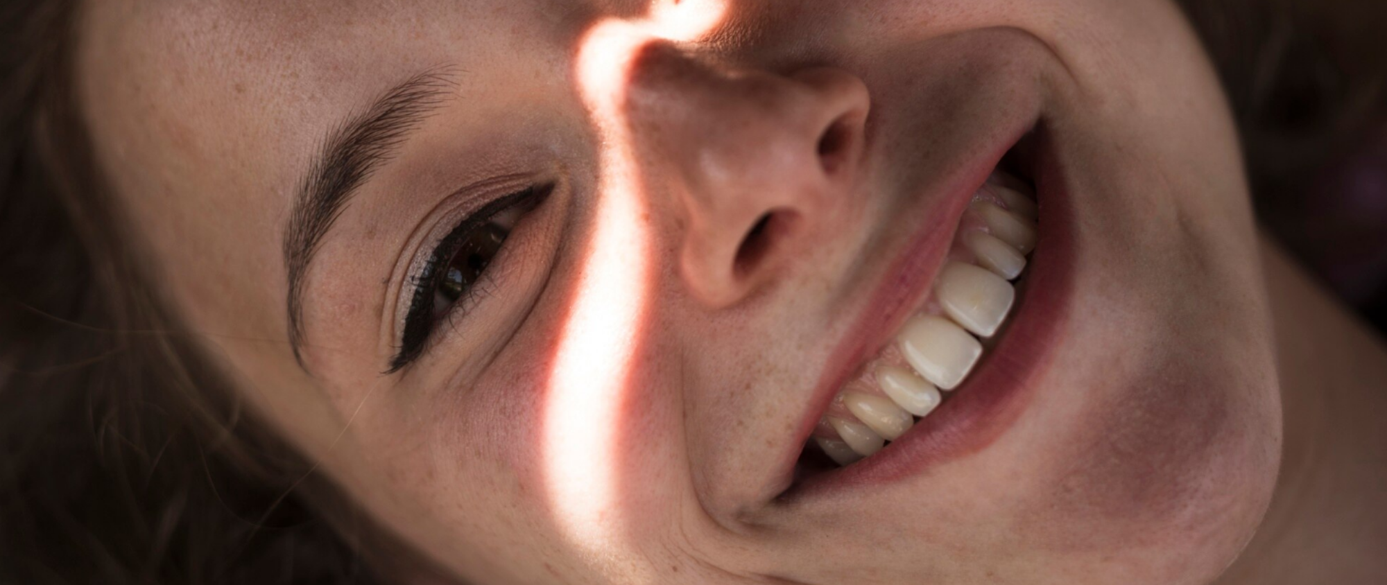 Nahaufnahme eines lachenden Gesichts mit Fokus auf gesunde, weiße Zähne.