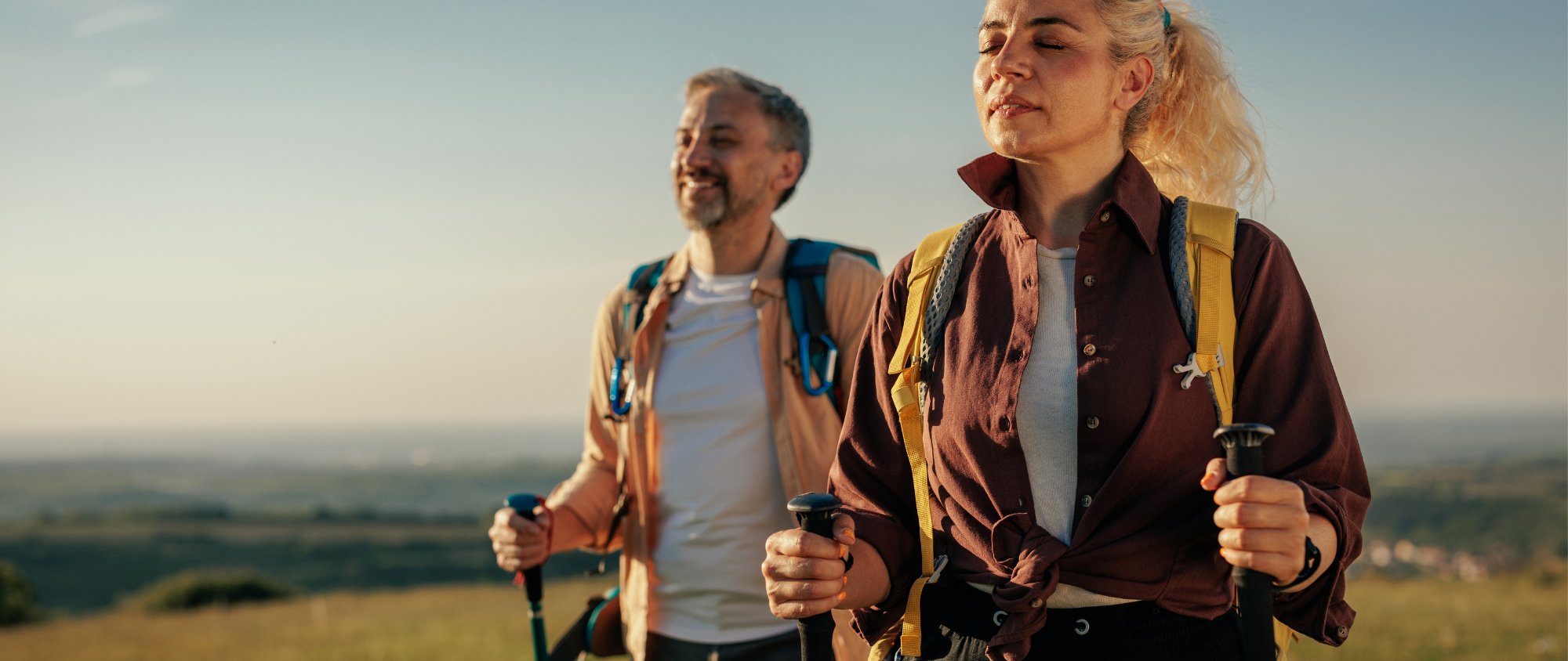 Zwei Personen beim Wandern in der Natur bei Sonnenuntergang.