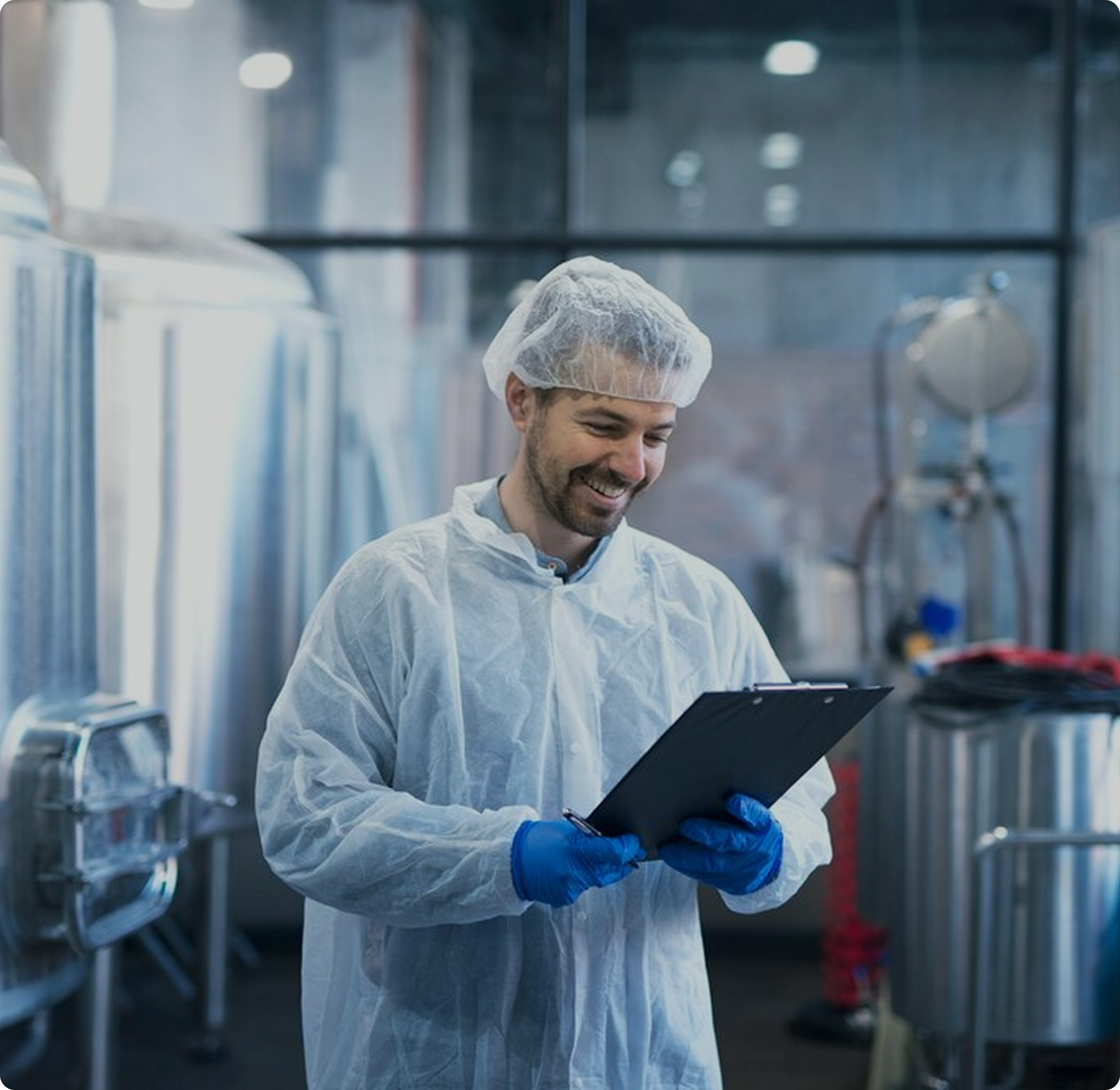 Ein Arbeiter in Arbeitskleidung mit weißem Kittel und Handschuhen, der eine Mappe und einen Stift in der Hand hält
