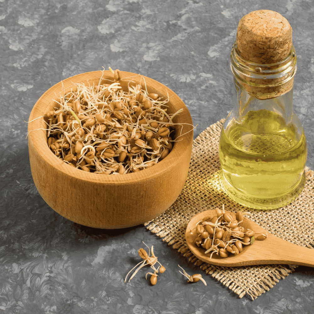 Weizenkeim in einer Holzschale, daneben ein Löffel und eine Flasche mit Öl
