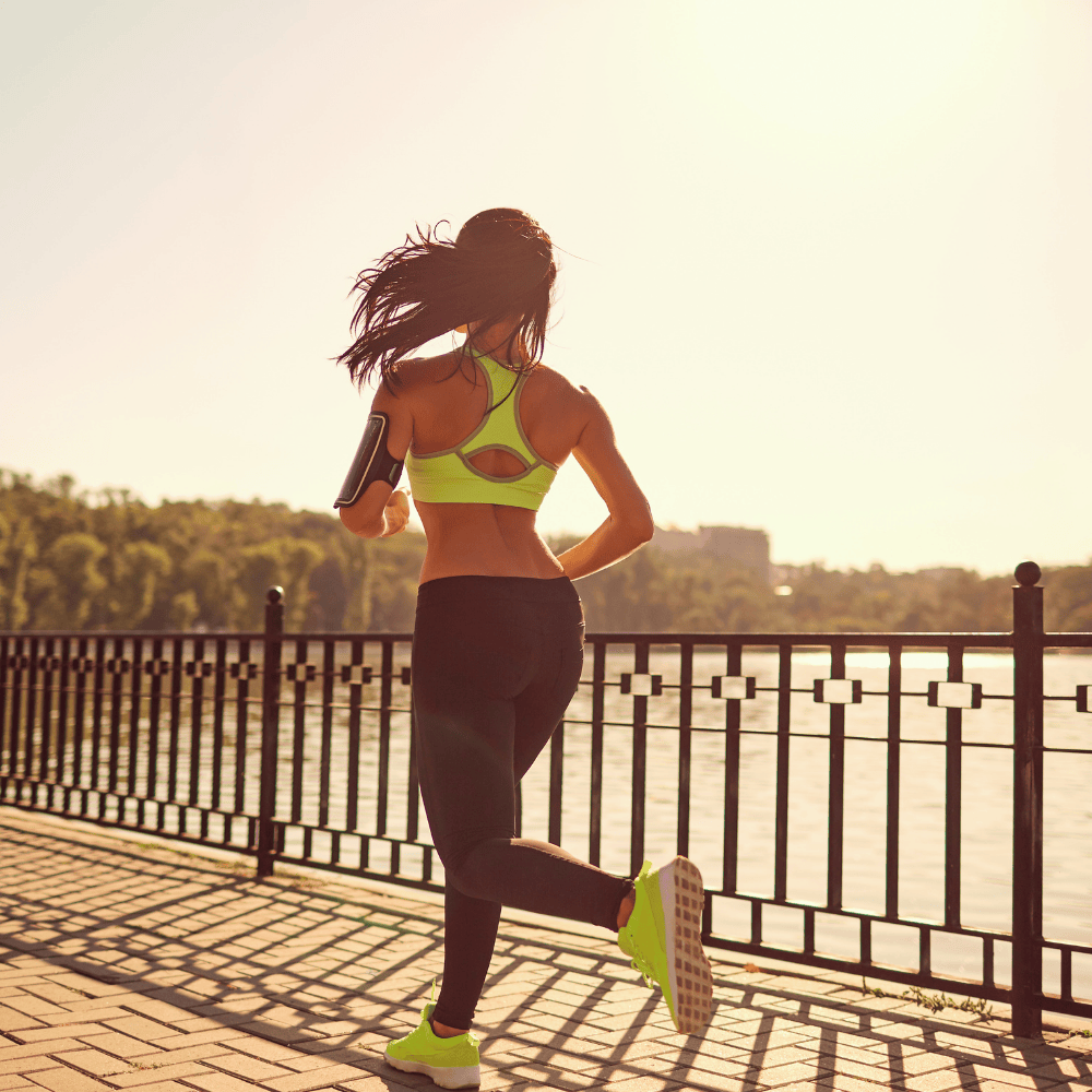 Ein sportlich gekleidetes Mädchen joggt auf einer Brücke über einem Fluss